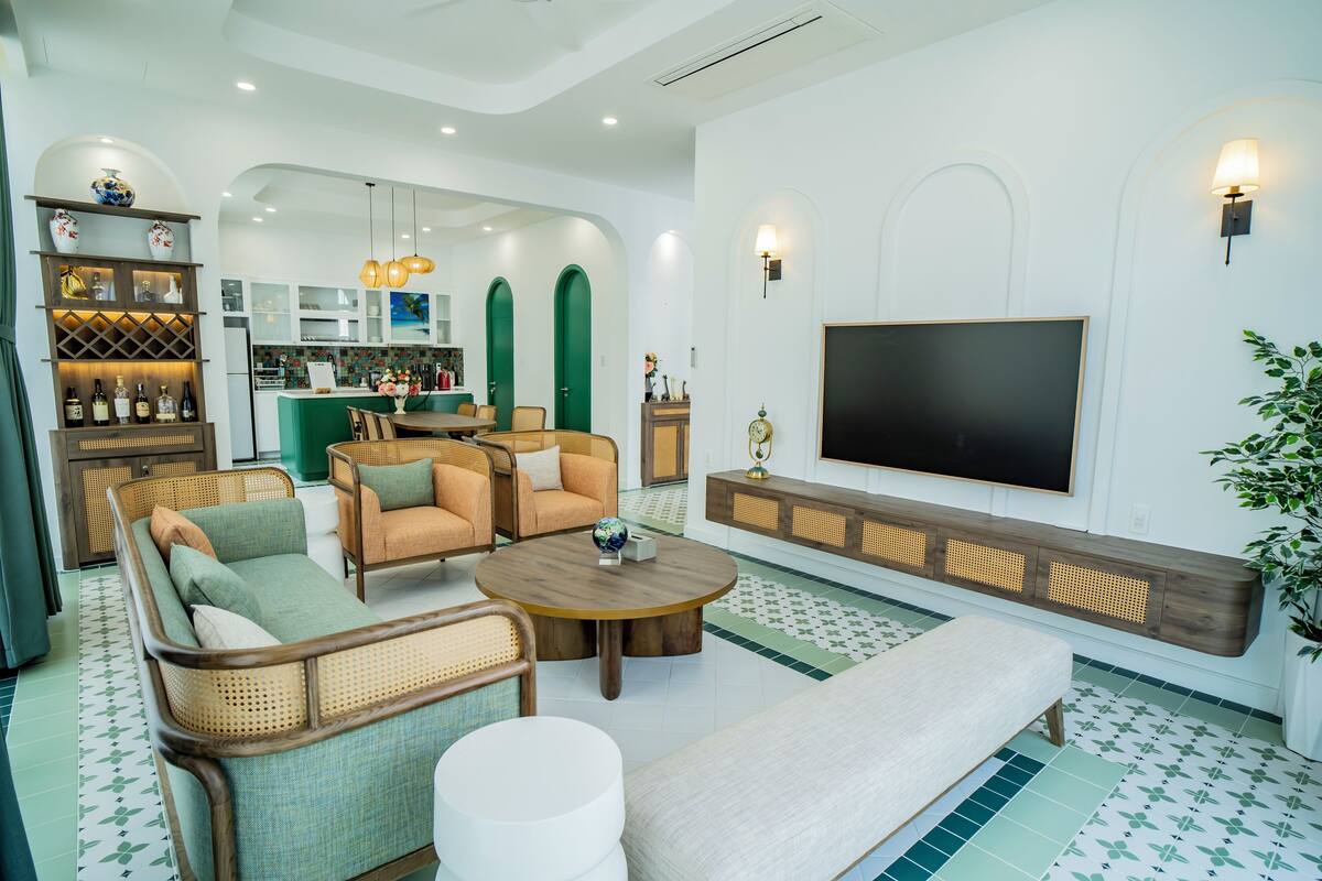 A modern living room with a sofa, armchairs, a coffee table, and a TV.