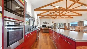 A spacious kitchen with red cabinetry, a large island, and a high ceiling with exposed beams.