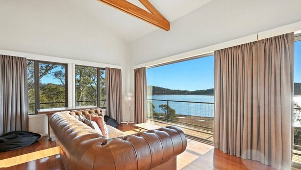 A modern room with a leather sofa, large windows, and a view of a lake.
