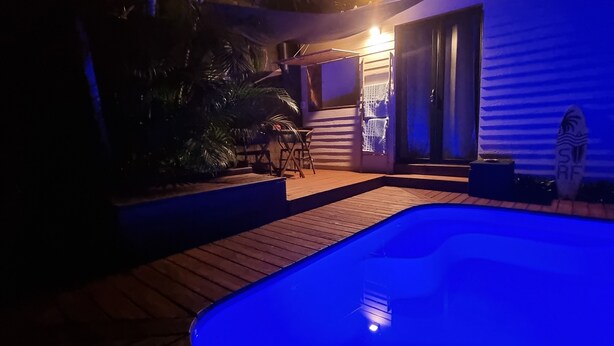 A pool area with a hot tub, wooden deck, and a covered seating area with a table and chairs. - Private Bungalow ZANANAS (97435)