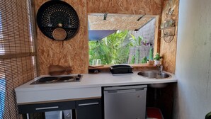 A compact kitchen with a built-in stove, a sink, and a window overlooking greenery. - Private Bungalow ZANANAS (97435)