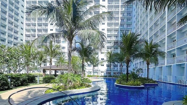Una piscina rodeada de palmeras y modernos edificios de apartamentos.