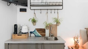 Una cocina moderna con televisión integrada, cafetera, bloque de cuchillos y estante colgante para plantas.