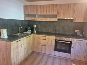 A kitchen with wooden cabinets, a built-in oven, and a coffee maker. - Apartment Predigtstuhl for 2 persons, 50 sqm, balcony with unobstructed view of the mountains (Bad Reichenhall)
