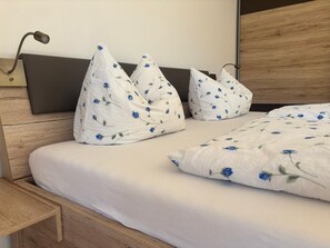 A neatly made bed with a white duvet and pillows featuring a blue floral pattern, a wooden headboard, and a bedside table with a lamp. - Apartment Predigtstuhl for 2 persons, 50 sqm, balcony with unobstructed view of the mountains (Bad Reichenhall)