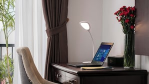 A desk with a laptop, a lamp, and a vase of flowers. - MIBEE Hotel (Hanoi)