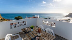 A terrace with a table and chairs overlooking the sea.