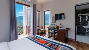 Habitación de hotel con cama, escritorio, televisión y baño con espejo y lavamanos.