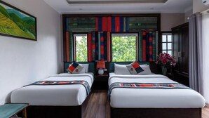 Habitación de hotel con dos camas, un ventanal con cortinas, un cuadro en la pared y un florero con flores.