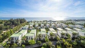 A resort with multiple white buildings, green roofs, and palm trees.