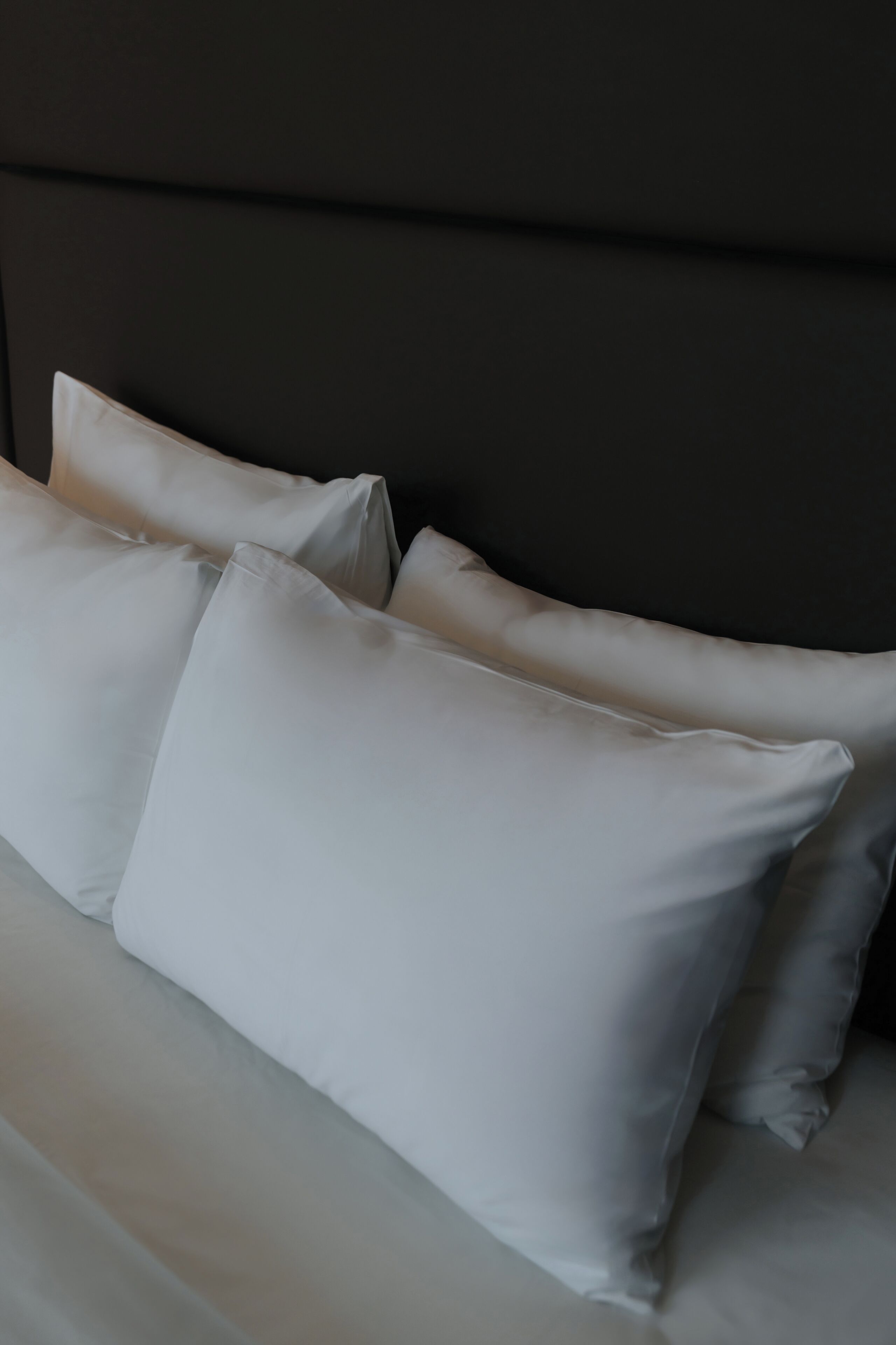 A bed with white pillows and a dark headboard.