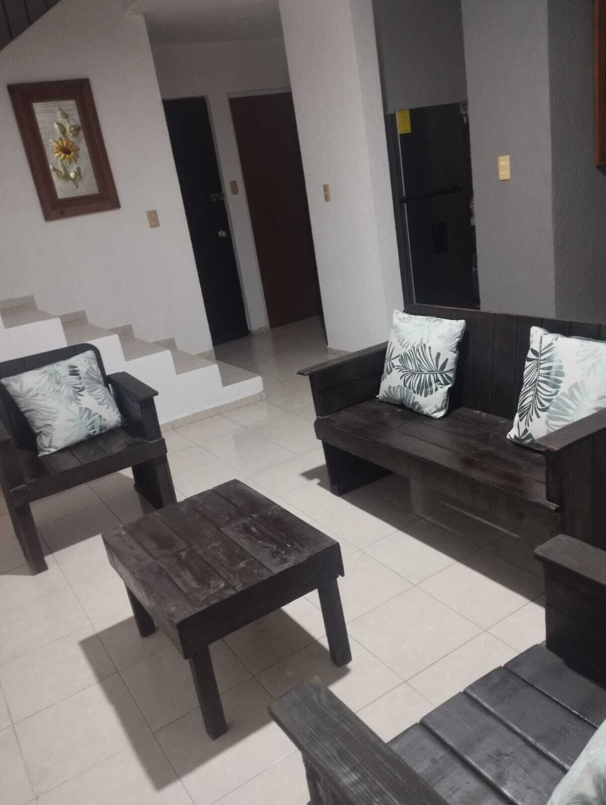 A modern living room with a dark wooden sofa set, a matching coffee table, and a patterned throw pillow.