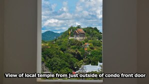 Vue d’un temple local, prise de l’extérieur d’un immeuble d’appartements, entouré d’une végétation luxuriante et de collines.