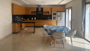Une cuisine moderne avec des meubles en bois, une table à manger avec des chaises et une grande fenêtre qui laisse entrer la lumière naturelle.
