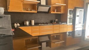 Une cuisine moderne avec des meubles en bois, un plan de travail noir et des appareils électroménagers en acier inoxydable, notamment un réfrigérateur et un four.