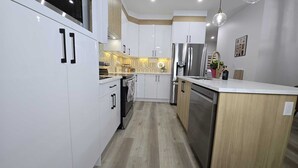 Een moderne keuken met witte kastjes, roestvrijstalen apparatuur en een houten aanrecht.