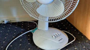 A white standing fan with a circular base and a power cord.