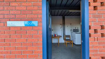 A laundry room with a sign, a washing machine, a chair, and a table.