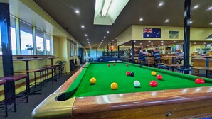 A pool table with balls, a bar area, and a flag on the wall.