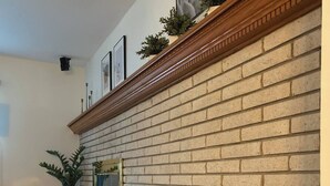 Un salon doté d’une cheminée en briques, d’une cheminée en bois et d’un espace détente avec des coussins.