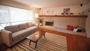 Un salon comprenant un canapé, une table basse, une cheminée et une vue sur l’extérieur.