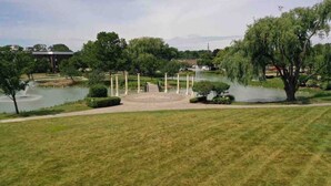 Un parc avec une fontaine, des arbres et un étang.