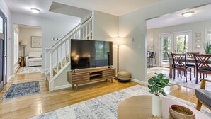 Ein modernes Wohnzimmer mit Flachbildfernseher, einer Holzunterhaltungseinheit und einer Treppe zu einer anderen Ebene.