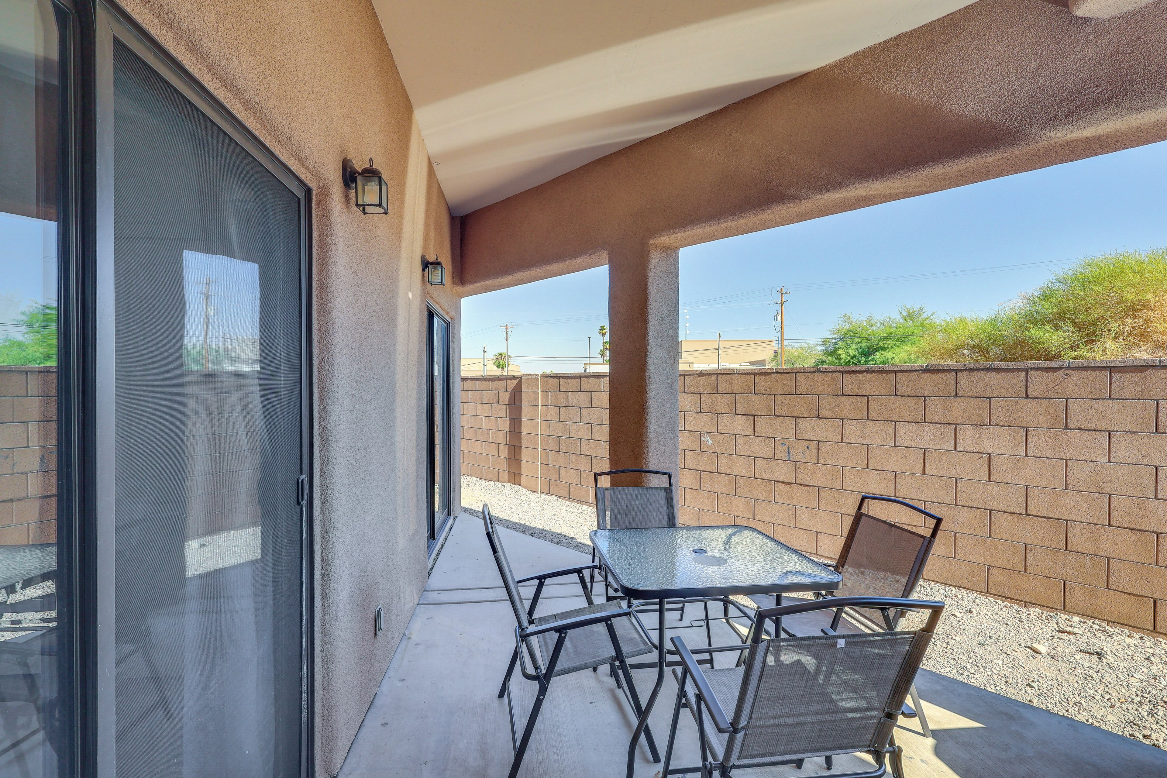 A covered patio with a table and chairs, a sliding glass door, and a brick wall.