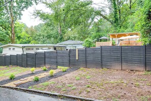 A fenced backyard with a wooden deck, a small garden area, and a house in the background.