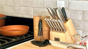 A kitchen counter with a cutting board, a grater, a knife block, and a measuring cup. - Modern Downtown Suite - Walking Distance to Restaurants, Shops, & Grocery Stores (Golden)