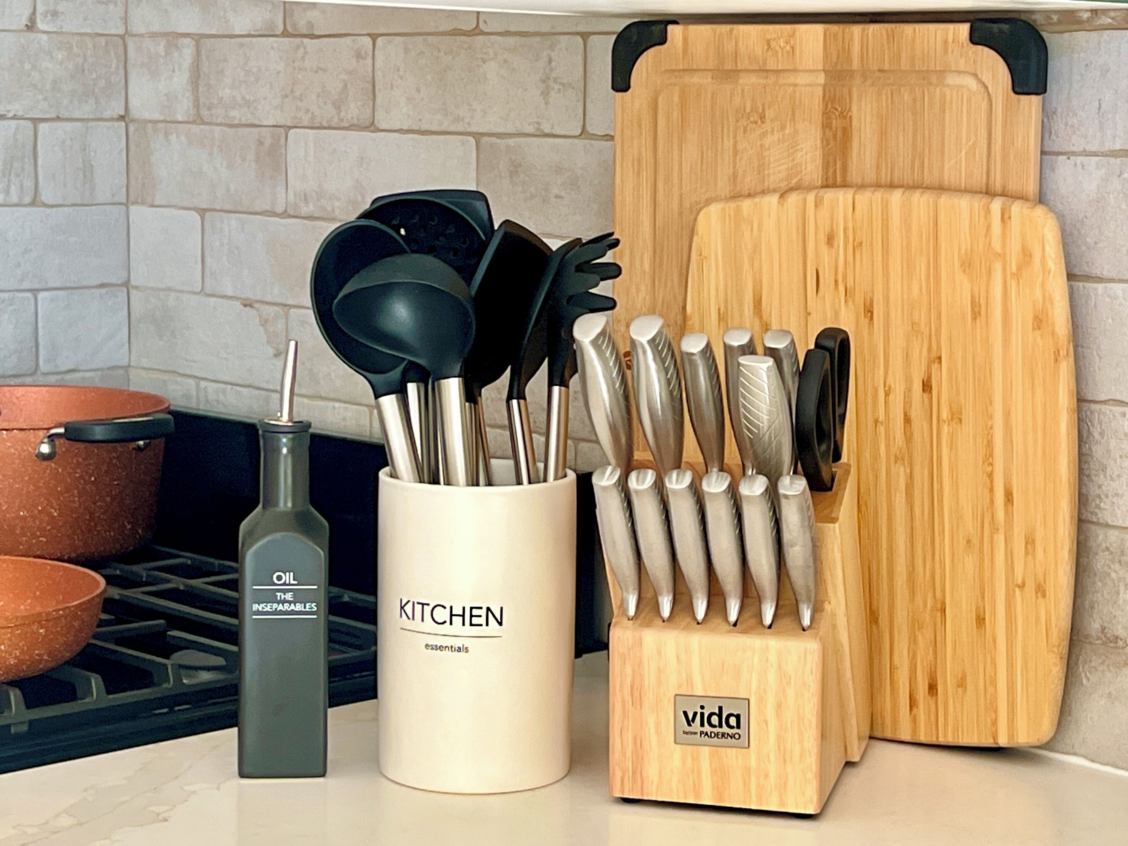 A kitchen counter with a white container labeled "KITCHEN essentials," a wooden cutting board, and a knife block.