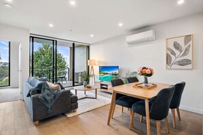 Una sala de estar moderna con sofá, mesa de comedor, sillas y televisor.