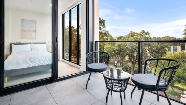 A balcony with a bed, two chairs, and a table.