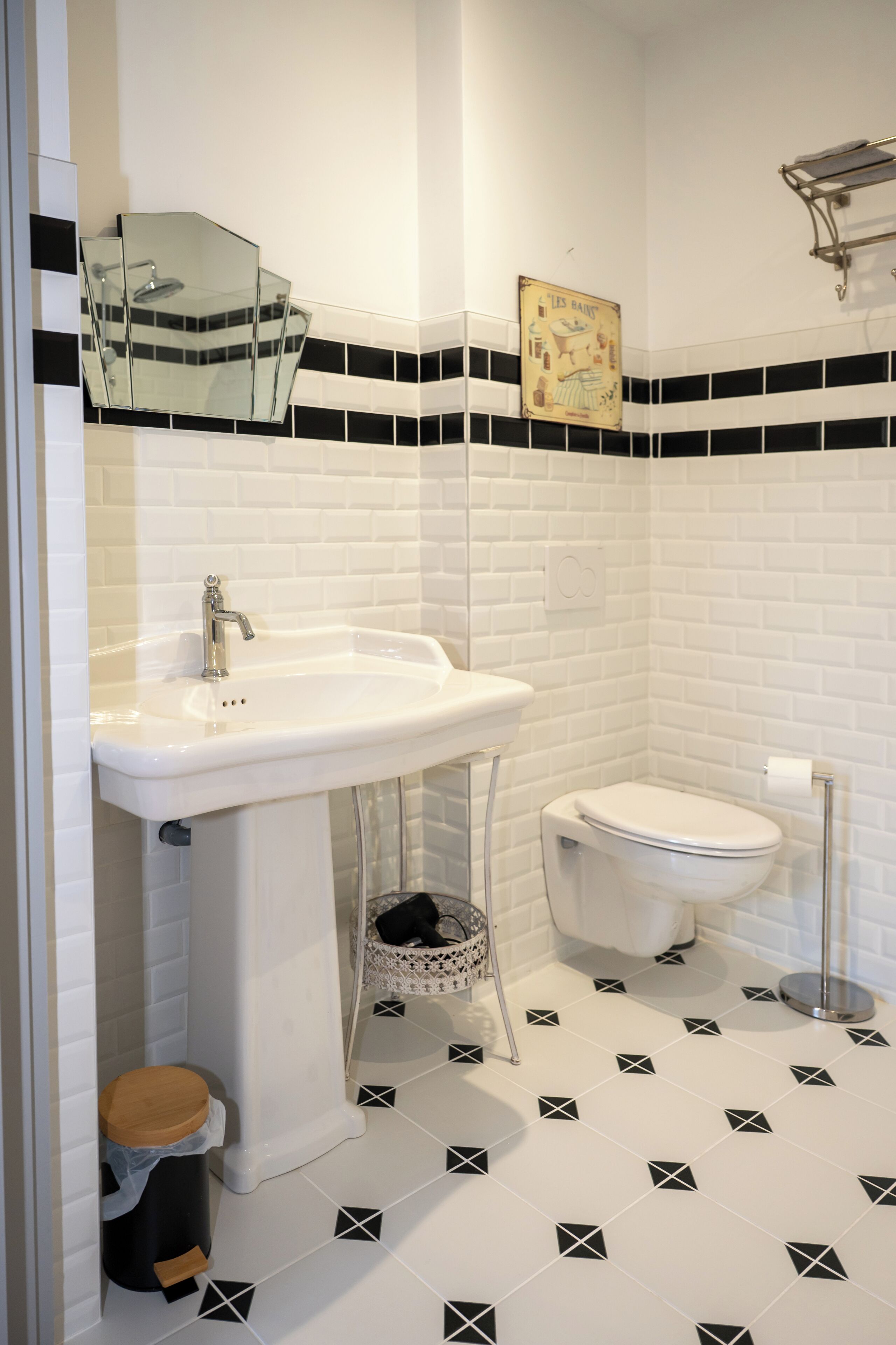 A bathroom with a white sink, toilet, and a small trash bin.