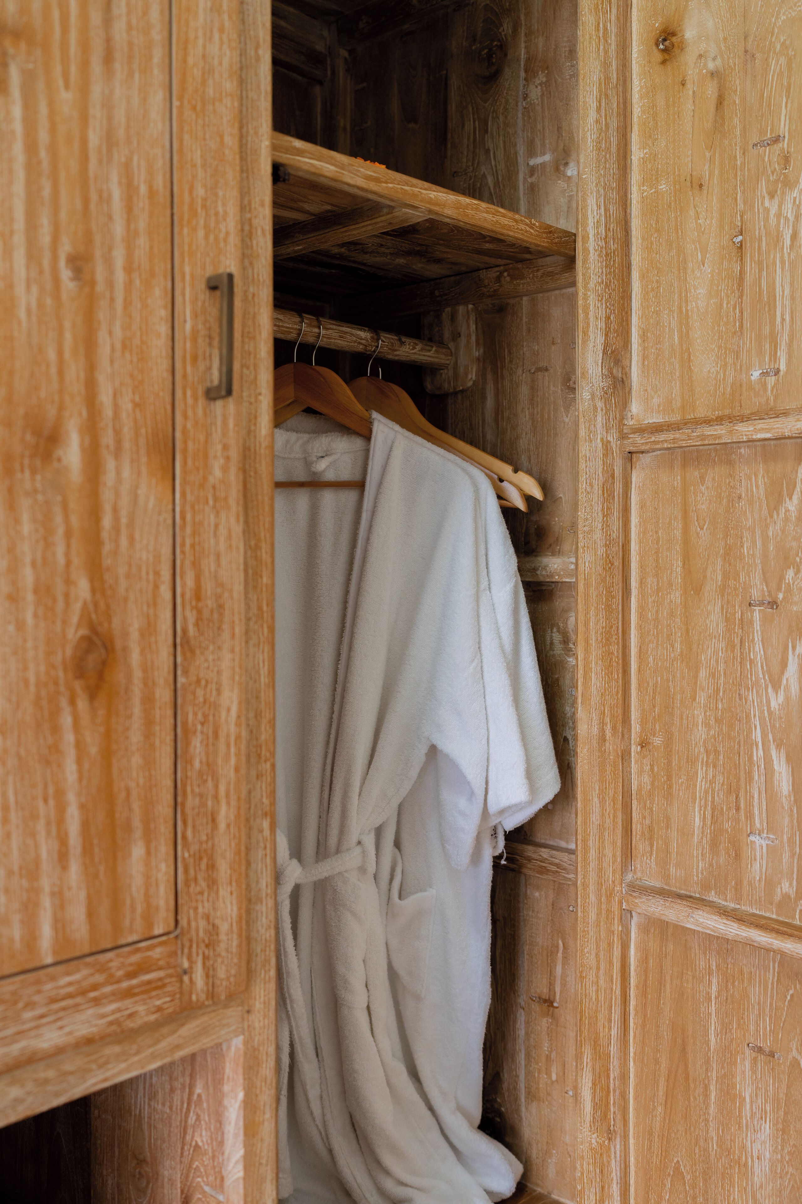 A wooden wardrobe with a hanging robe.