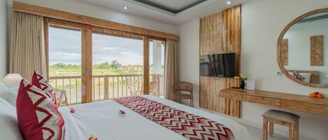 Habitación de hotel con una cama grande, un escritorio de madera, un televisor y un balcón con vistas.