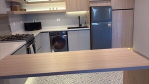 A modern kitchen with a dishwasher, stove, and refrigerator.