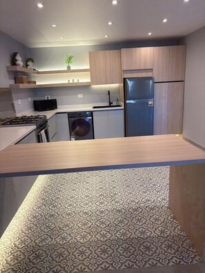 A modern kitchen with a dishwasher, stove, and refrigerator.