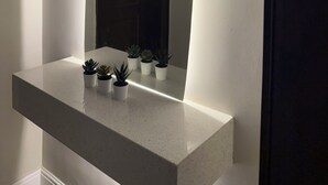 A bathroom with a white vanity, a mirror, and several potted plants.
