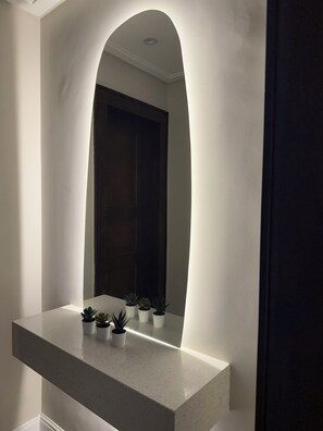 Une salle de bain avec un meuble-lavabo blanc, un miroir et plusieurs plantes en pot.