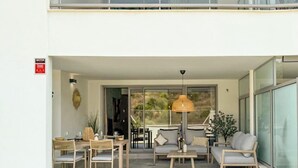 Una casa moderna de dos pisos con balcón, un área de comedor con mobiliario exterior y un césped bien cuidado.
