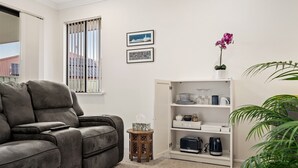 A living room with a grey sofa, a white bookshelf, and a small table with a tissue box.