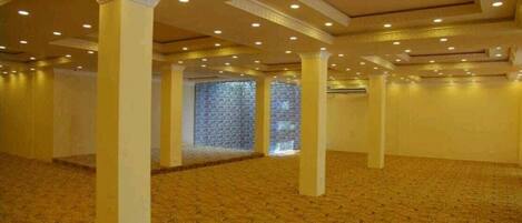 Un salón amplio con alfombra estampada, columnas e iluminación empotrada.