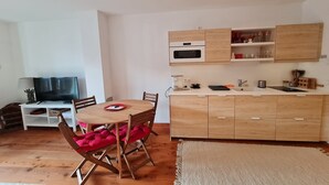 A compact living space with a dining area, a kitchenette, and a television. - Bad Gastein Fallside Apartment (Bad Kleinkirchheim)