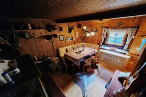 A rustic wooden cabin interior with a dining area, a window with curtains, and various hunting trophies on the walls. - Idyllic cabin with sauna (Bad Kleinkirchheim)