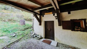 A rustic building with a wooden ceiling, a door, and a small porch area.