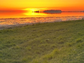 Ein Sonnenuntergang über einem grasbewachsen Feld mit einer entfernten Insel.