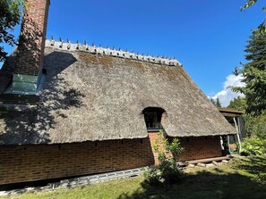 Ein Gebäude aus Ziegeln mit einem strohgedeckten Dach und einem kleinen Fenster.