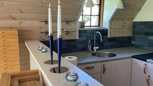 Una cocina con armarios de madera, un lavabo, una ventana y velas sobre la encimera.