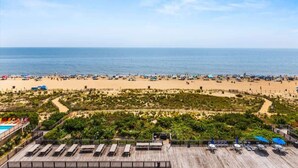 A beach view with a wooden deck, lounge chairs, and umbrellas.